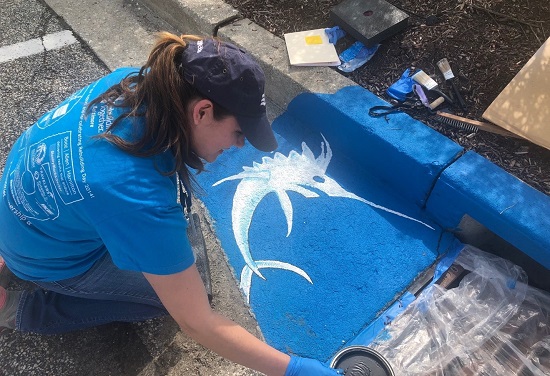 team member painting storm drain