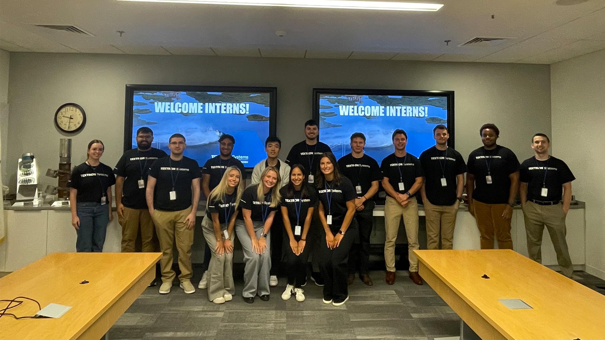 Interns posing in front of a screen that reads "welcome interns"