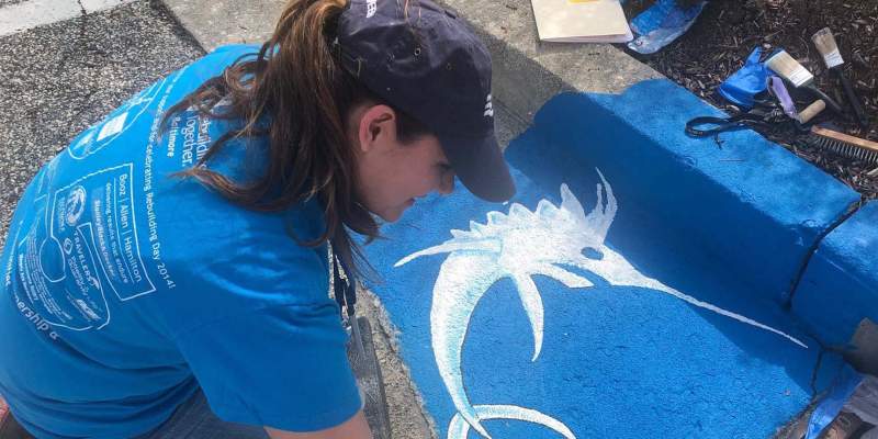 team member painting storm drain