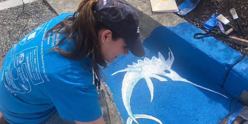 team member painting storm drain